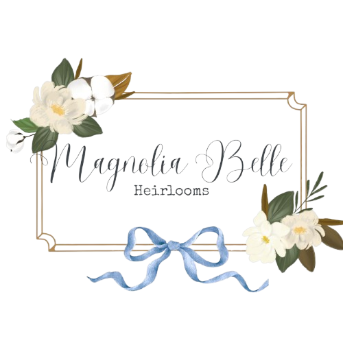 Magnolia Belle Heirlooms logo with magnolia flowers, gold frame, and blue ribbon